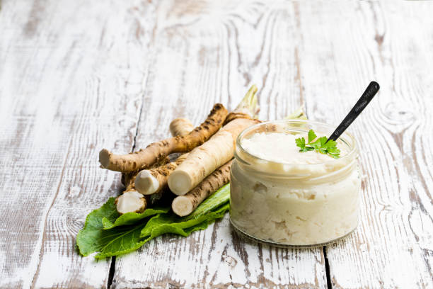Spicy horseradish sauce in small glass jar on wooden table Spicy  horseradish sauce in small glass jar on wooden table horseradish stock pictures, royalty-free photos & images