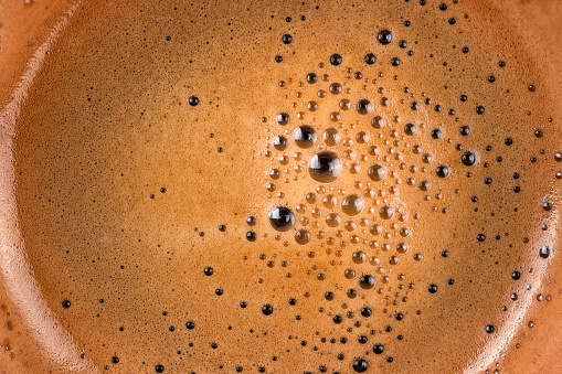 Coffee foam into cup extreme close up. Macro texture and background