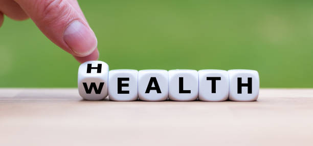 mano está convirtiendo un dado y cambia la palabra "salud" a la "riqueza" - capital letter fotos fotografías e imágenes de stock