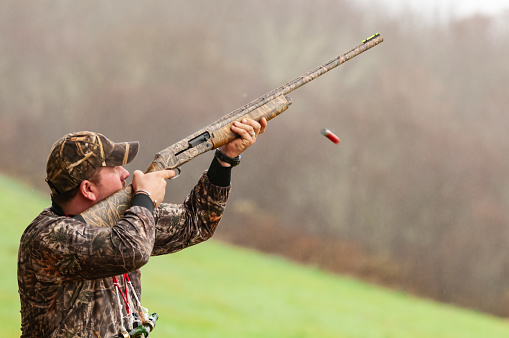 Glenelg, NS, Canada - November 6, 2010 - A hunter takes aim and fires a shotgun at thrown clay skeet at a hunting camp.