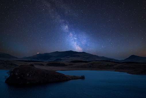 Stunning vibrant Milky Way composite image over landscape of Llyn y Dywarchen lake in Snowdonia National Park