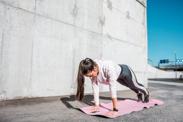 istock Young woman in plank position outdoors and using smart phone 1062283502