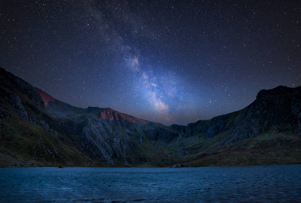 istock Digital composite Milky Way image of Beautiful landscape image of Llyn Idwal and Devil's Kitchen in Snowdoina 1062286350