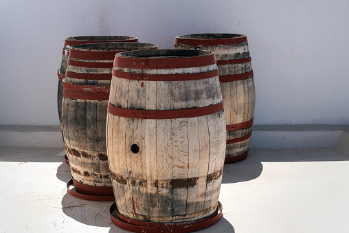 Three old wooden barrels staying near the wall. Santorini island, Greece