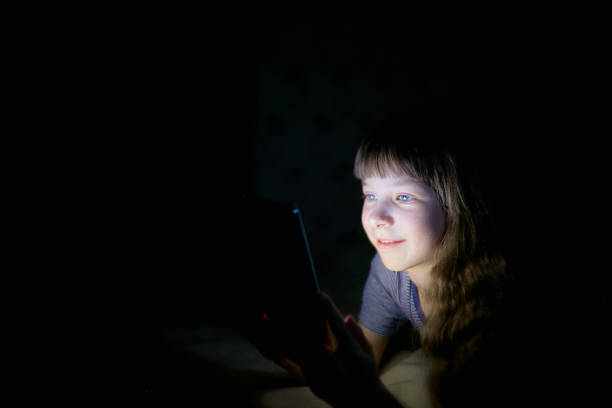 istock little girl with a tablet on the bed at night. 1062298628
