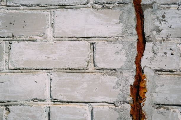 istock Crack on an old white brick wall, texture abstraction 1062299348