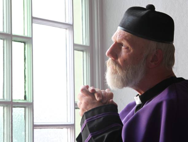 istock senior priest praying at church window 1062299364