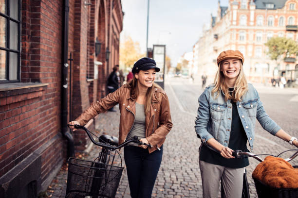 Friends with Bicycles Close up of two friends leading their bicycles through the city swedish woman stock pictures, royalty-free photos & images