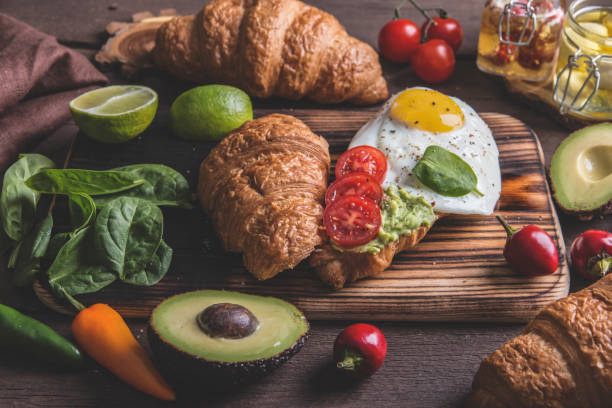 istock croissant with guacamole avocado, fried egg and tomato, spinach leaves. vegetarian dish 1062323930