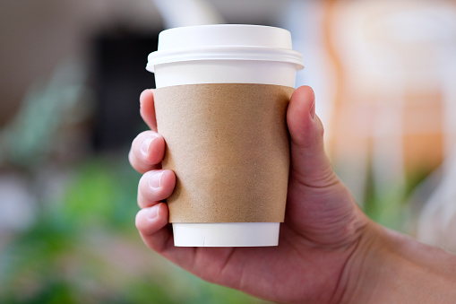 Hand holding brown paper cup.