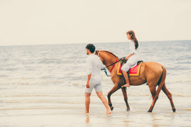 istock Young couple goes horse riding on tropical beach. 1062334202