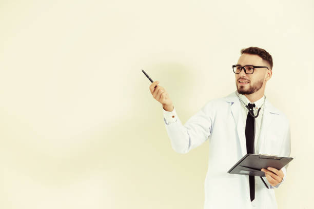 istock Male doctor points pen at empty wall copy space. 1062335194