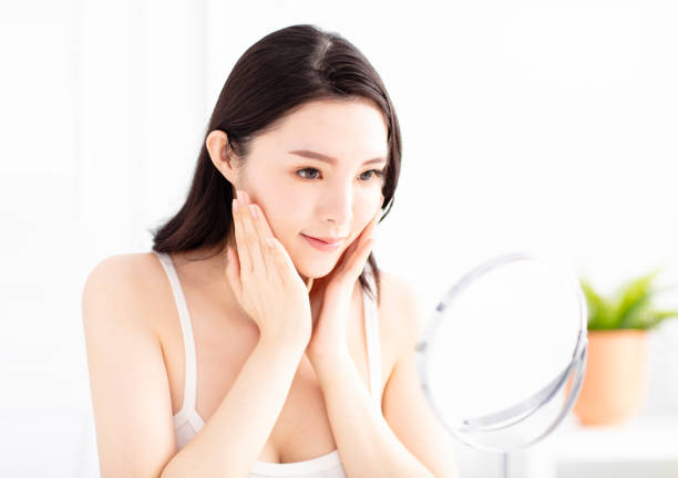 istock young woman looking in mirror on face 1062338700