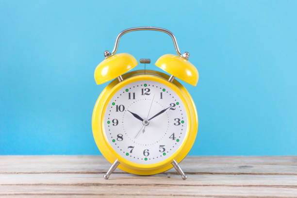 istock Retro alarm clock on wooden desk and blue background 1062344214