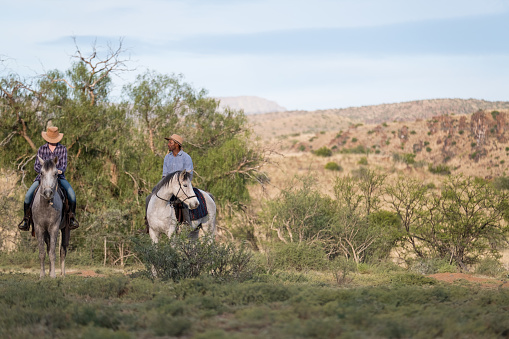 A female farm owner heads out on horseback with the African farm manager