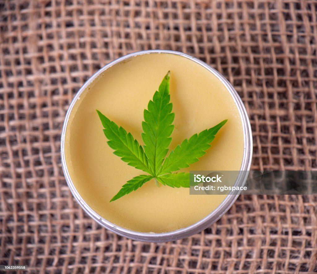 Cannabis hemp cream with marijuana leaf - cannabis topicals concept Detail of cannabis hemp cream with marijuana leaf over burlap background - cannabis topicals concept Moisturizer Stock Photo