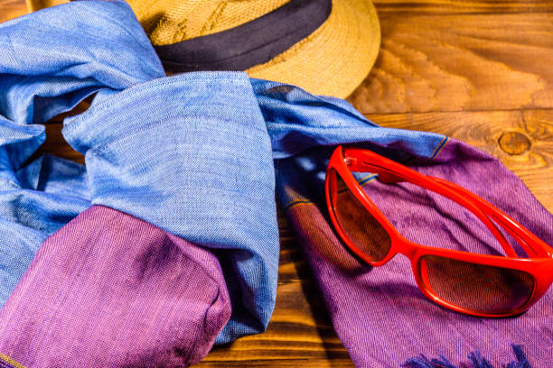 istock Scarf, straw hat and eyeglasses on wooden table 1062381540