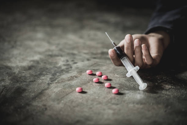 woman hand of a drug addict and a syringe with narcotic syringe lying on the floor, overdose, drug concept. - narcotic teenager cocaine drug abuse imagens e fotografias de stock