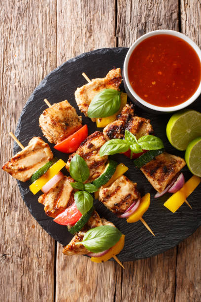 istock spicy grilled chicken kebabs with vegetables served with ketchup close-up. Vertical top view 1062402114