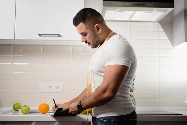 спортивный диетолог пишет в блокноте на кухне - stationary pen orange work tool стоковые фото и изображения