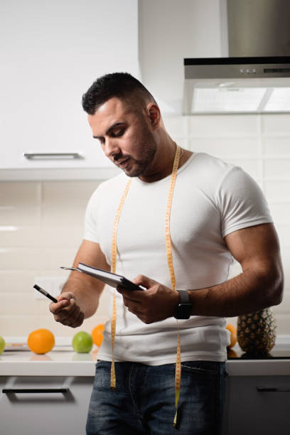 спортивный диетолог пишет в блокноте на кухне - stationary pen orange work tool стоковые фото и изображения