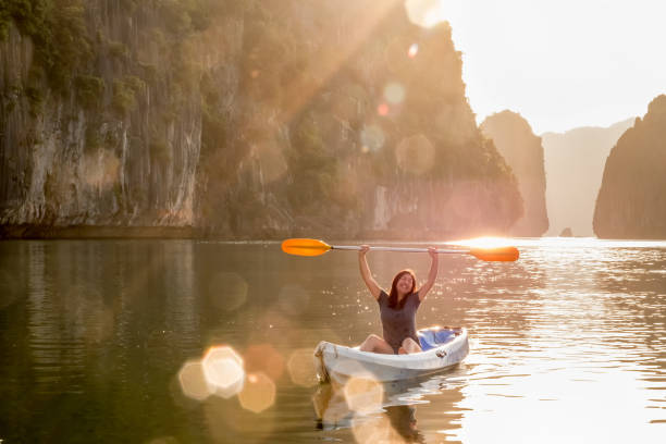 istock Young Asian Woman Holds Paddle Overhead While Kayaking in Vietnam 1062409940
