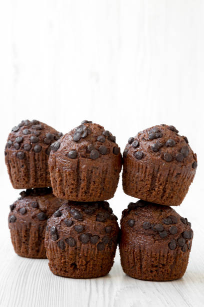 istock Chocolate muffins over white wooden background, side view. Closeup. 1062419828