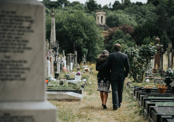 Sad couple walking through a cemetery Sad couple walking through a cemetery Funeral stock pictures, royalty-free photos & images