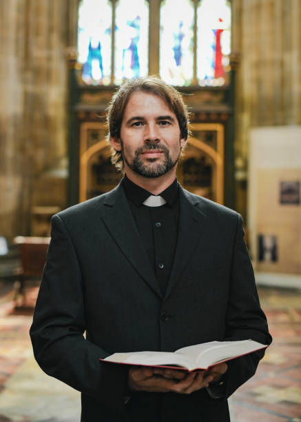 Color image depicting a front view of a mid adult man kneeling and praying inside an Anglican church.