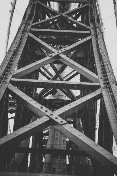 Vertical metal constructions of a bridge or crane, shot in black and white, viewed from low angle
