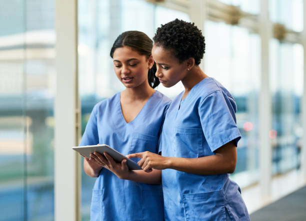 Researching news on a specific disease Shot of two medical practitioners using a digital tablet together in a hospital nurse stock pictures, royalty-free photos & images