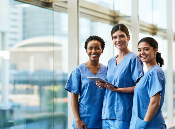 Technology facilitates our day-to-day duties Portrait of a group of medical practitioners using a digital tablet together in a hospital medical scrubs stock pictures, royalty-free photos & images