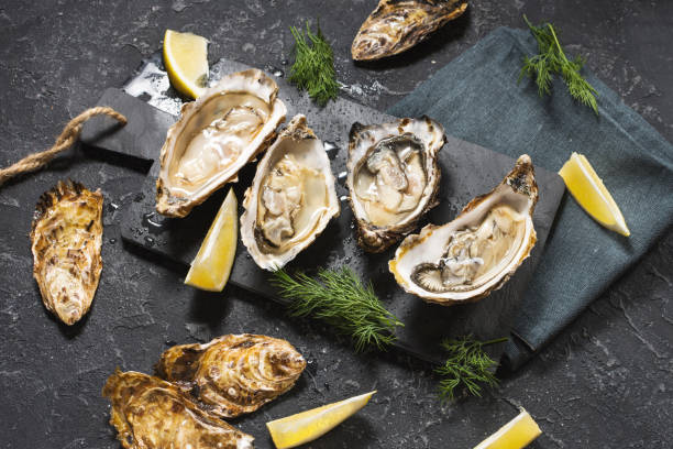 istock Opened Oysters with lemon on dark stone background 1062430754