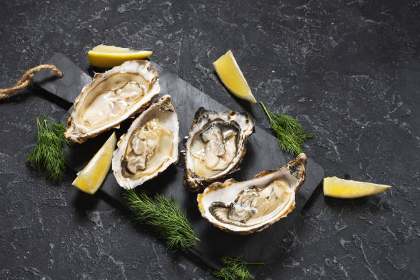 istock Opened Oysters with lemon on dark stone background 1062433590