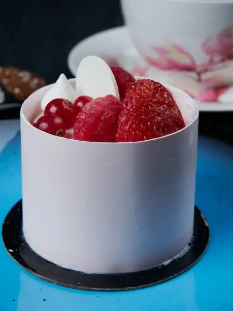White chockolate cake with strawberies, raspberries and redcurrants served on a blue plate