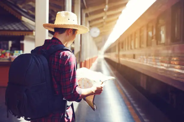 Man Traveler holding map and backpack while waiting for the train,Travel concept.copy space.