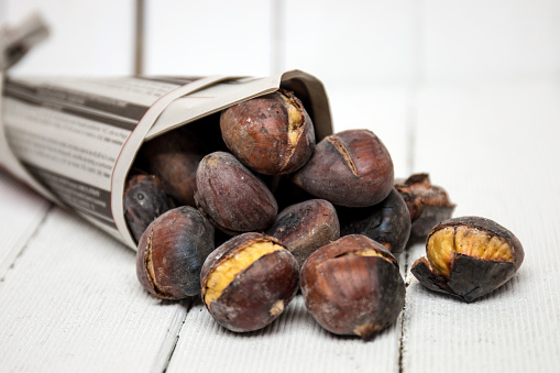 Close up view of some delicious hot toasted chestnuts wrapped on newspaper.