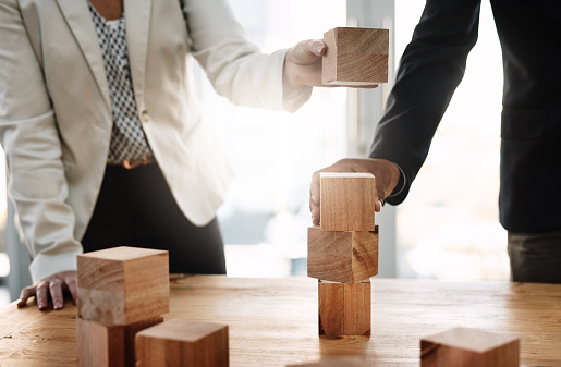 Shot of two unrecognizable businesspeople stacking wooden blocks together in an office