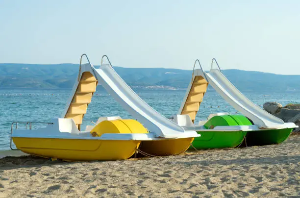 Pedal-boats with water slides on the beach.