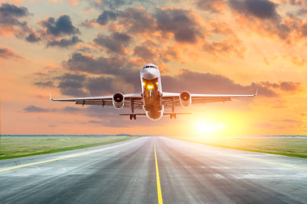 istock Airplane flying arrival landing on a runway in the evening during a bright red sunset. 1062473816