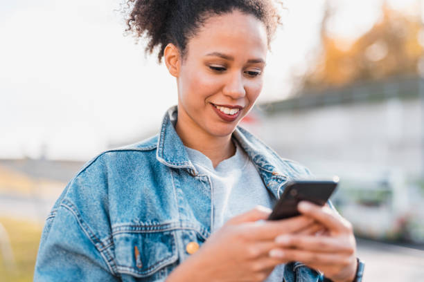 istock African woman using smart phone outdoors and smiling 1062477818