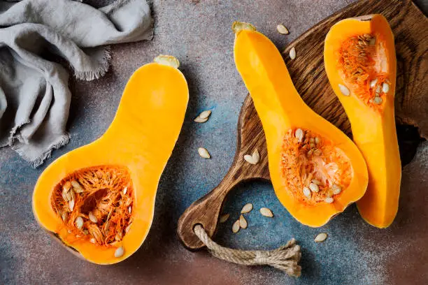Photo of Butternut squash on wooden board over rustic background. Healthy fall cooking concept