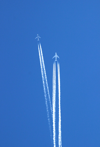 two large commercial aircrafts in the sky, condensation trails crossing each other