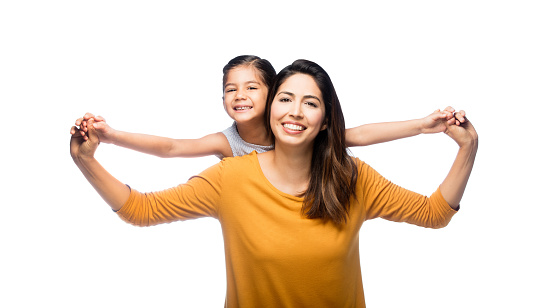 A young playful little girl on her mother's back laughing with her arms wide open on an isolated white background