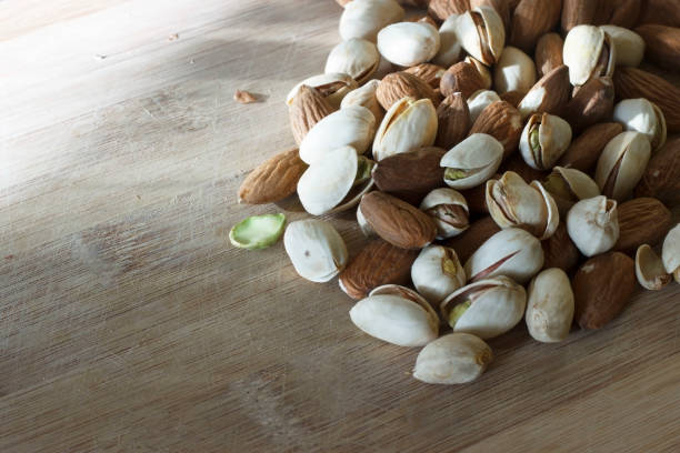 istock Pistachios and almonds on a wooden background 1062484344