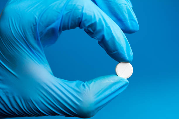 istock scientist  holding a pill with fingers in blue gloves. 1062490036