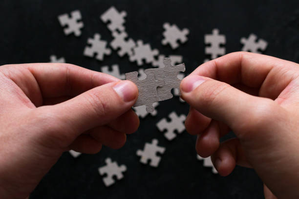 istock man holding two matching puzzle pieces on black background 1062495200