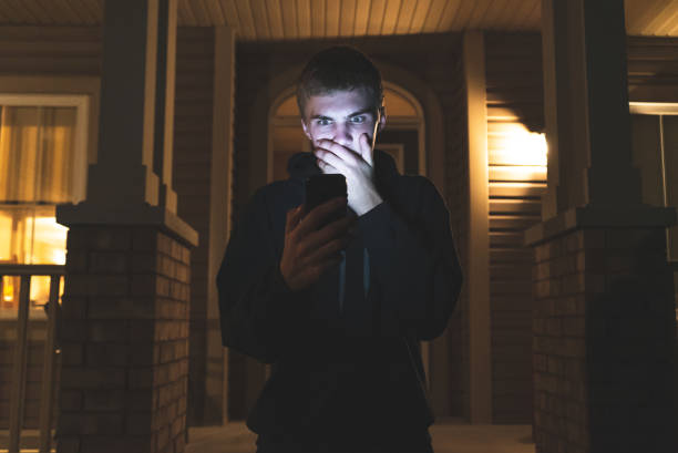 Shocked teenager on his mobile phone at night. stock photo
