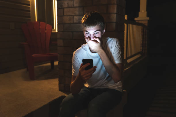 Shocked teenager on mobile phone at night. stock photo
