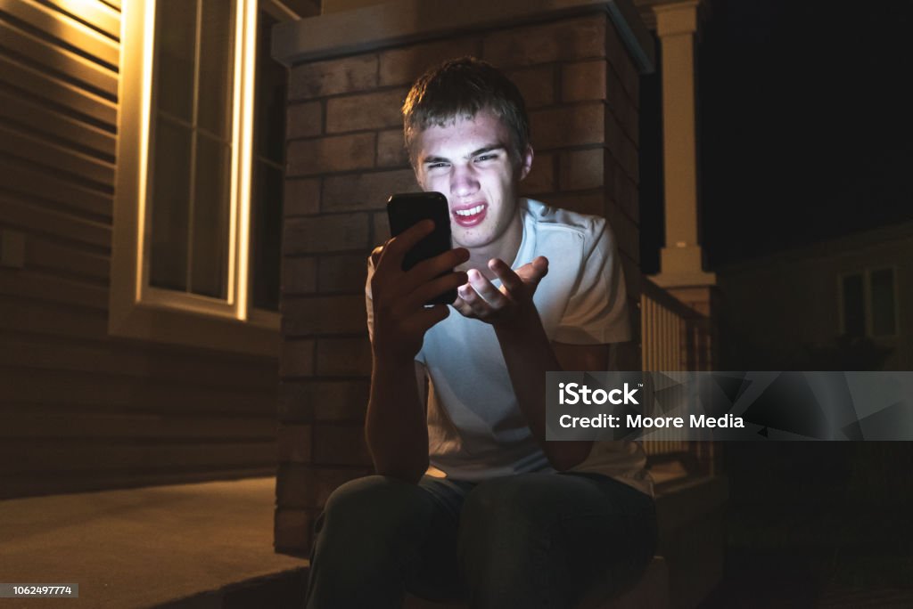 Adolescente sorprendido en móvil por la noche. - Foto de stock de Sexting libre de derechos